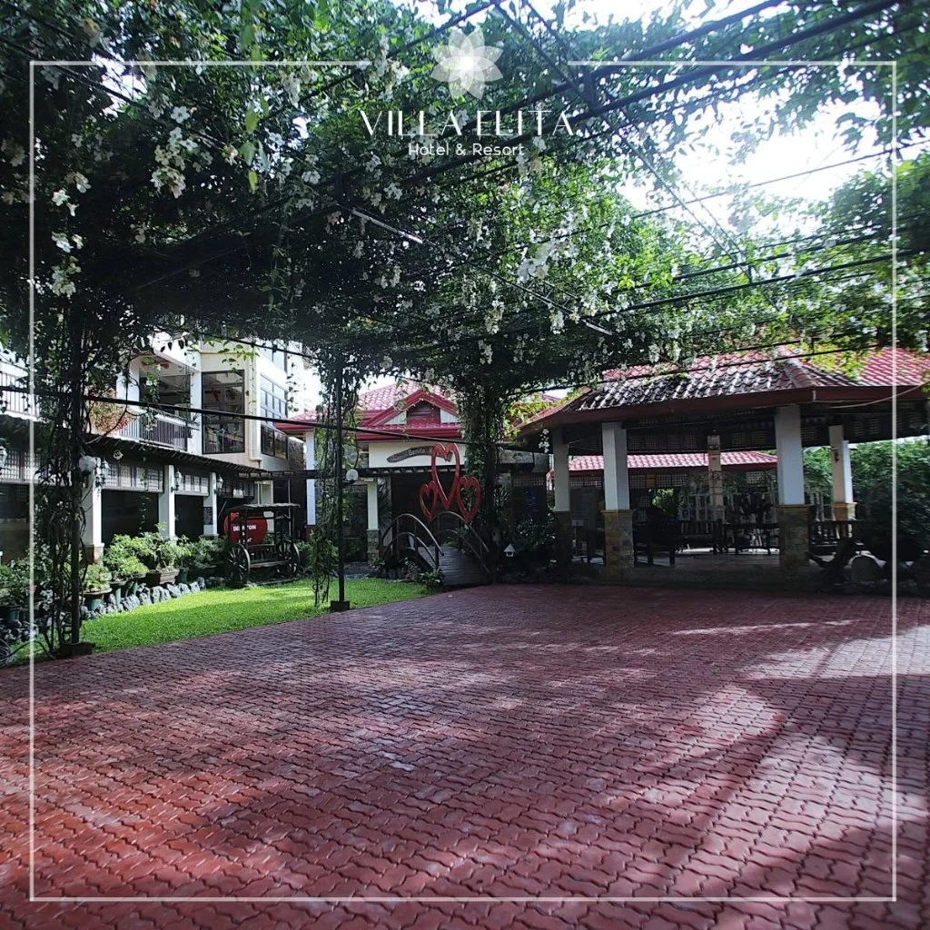 Courtyard at Villa Elita with red brick paving, vine-covered trellis, and pavilion