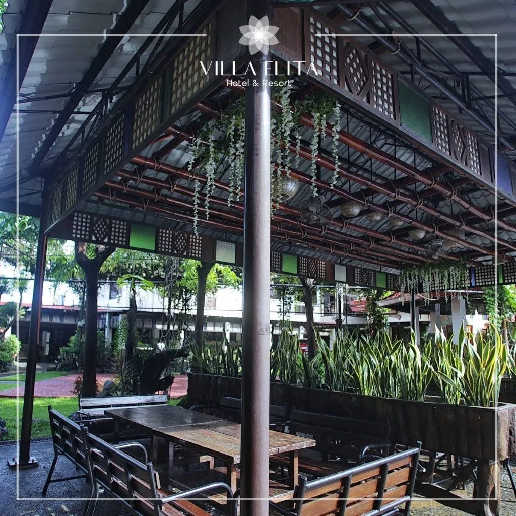 Outdoor dining pavilion at Villa Elita with wooden tables and tropical plants